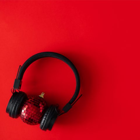 Headphones around a Christmas decoration on a red background
